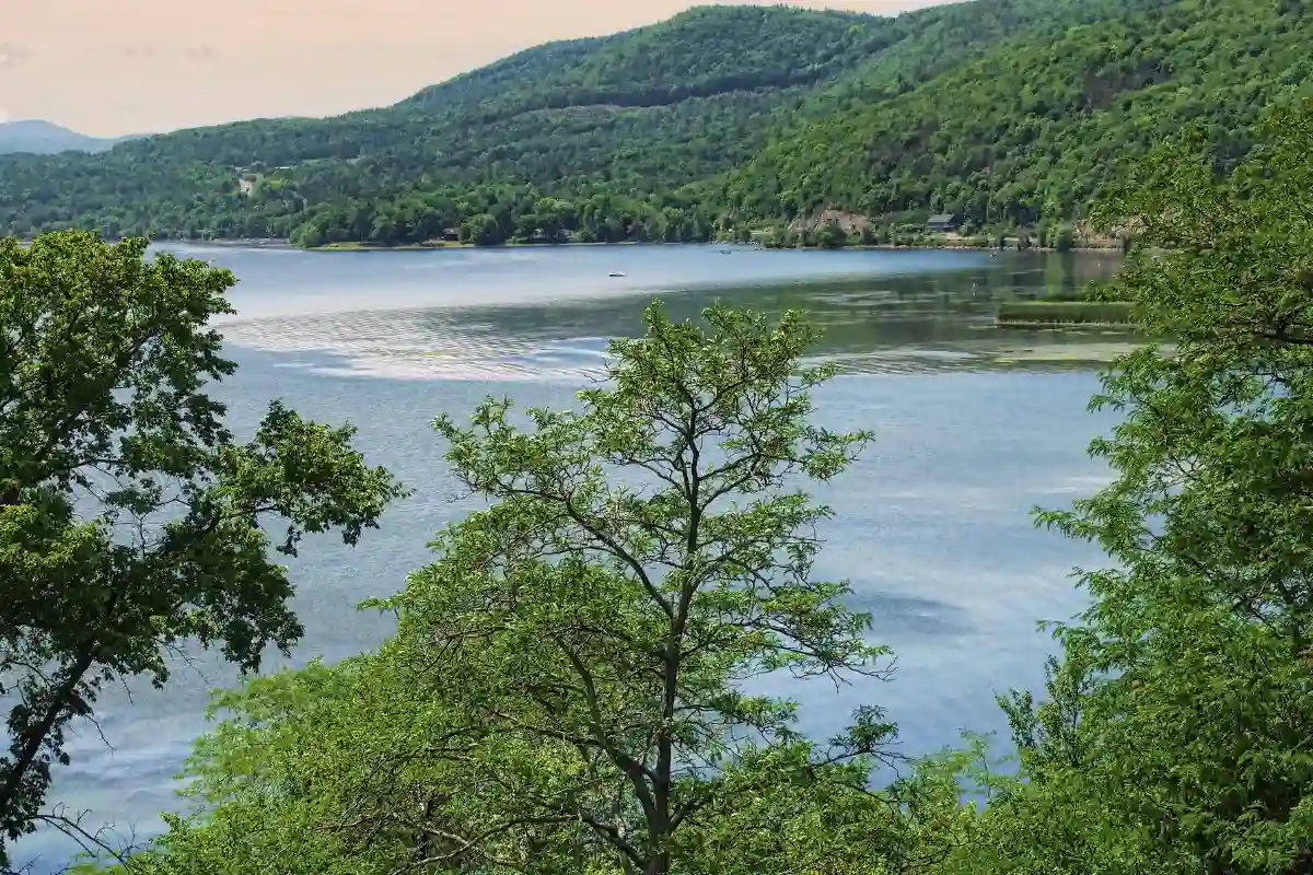 Lake Champlain with calm blue water and green Adirondack foothills, showcasing scenic shoreline views near Champlain, NY.