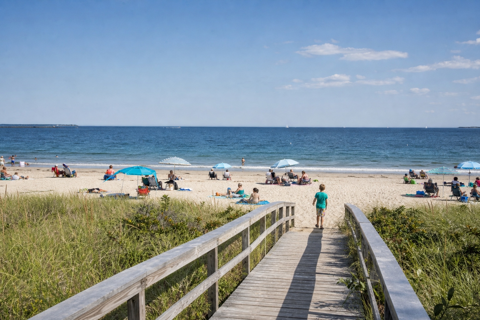 Wooden boardwalk leading to a sandy Cape Cod beach dotted with umbrellas and sunbathers.