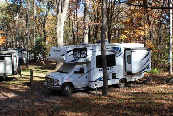 Wide-shot-of-an-RV-connected-at-a-pedestal-with-cord-and-hose-visible-scaled